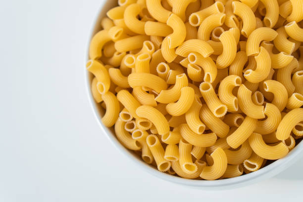istock Raw dry uncooked Elbow Macaroni pasta spaghetti on white background. Good for basil tomato pesto sauce Homemade fresh Italian food organic whole wheat vegan spaghetti noodle for a healthy meal 1250328973