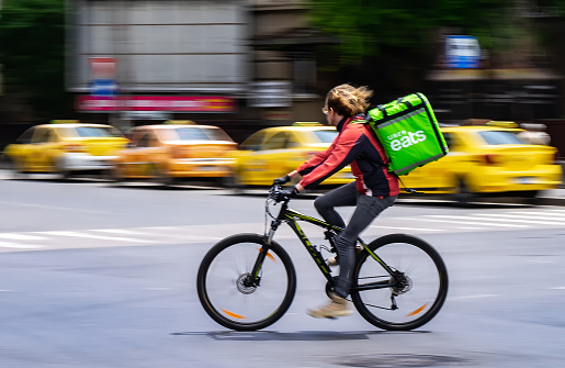 Bucharest, Romania - May 07, 2020: An Uber Eats food delivery courier on a bike in high speed. Restaurants are closed and only deliveries are allowed during the state of emergency due to coronavirus.