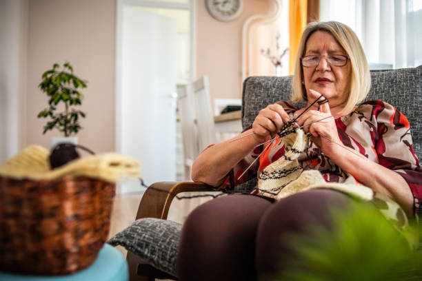 An older woman is knitting wool socks