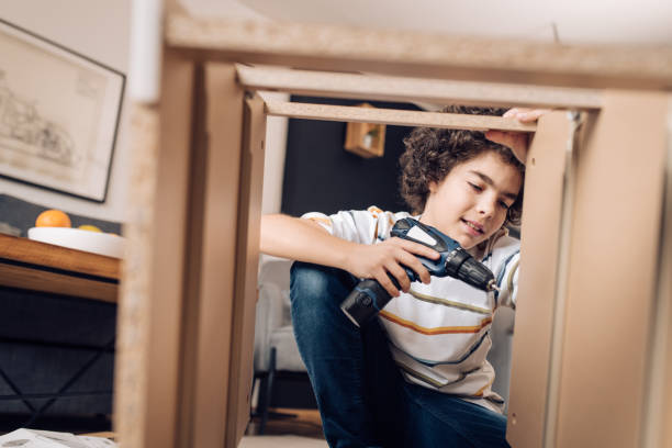 istock Boy using electric screwdriver to fold a wooden table at home 1250334157