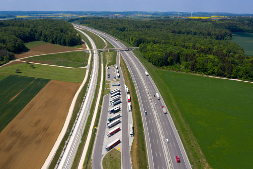 Aerial view of a multiple lane highway and row of trucks in the parking lot.
