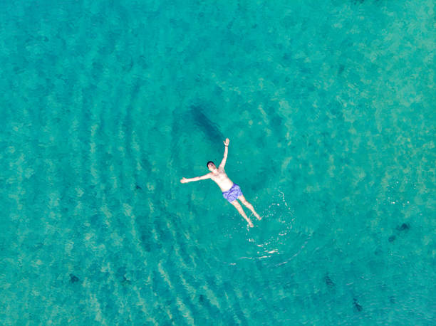 istock Aerial View Man Floating in Water and Relaxing 1250334920