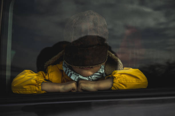 Sad boy with hunters cap sitting in car