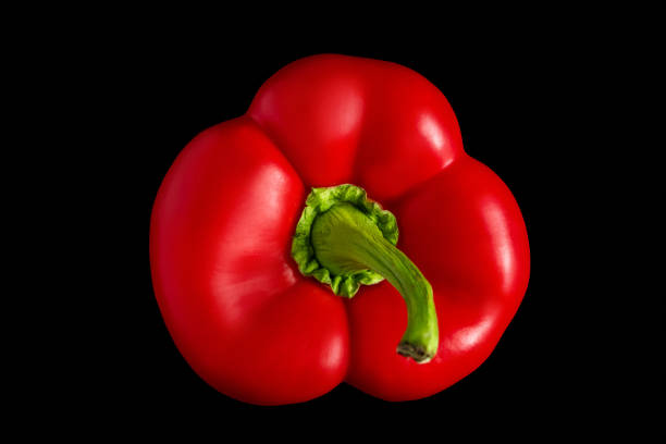 Photo of two red bell peppers over a wooden table.