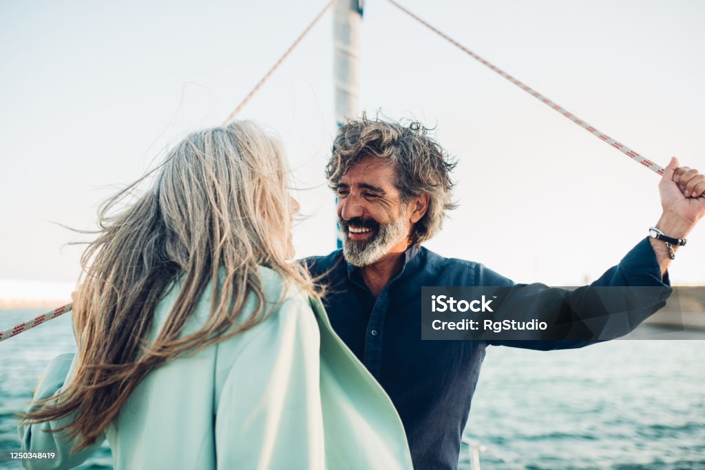 Mature man and his wife enjoying sailing with their yacht Senior couple in love enjoying cruising on their yacht. Mature Couple Stock Photo