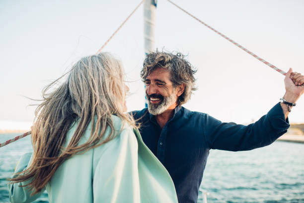 Mature man and his wife enjoying sailing with their yacht Senior couple in love enjoying cruising on their yacht. rich man stock pictures, royalty-free photos & images
