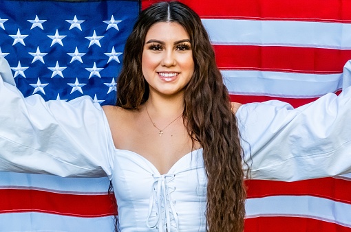 Smiling hispanic young woman holding a US flag