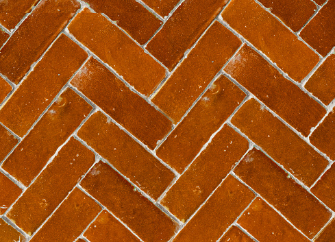 Close up shot of herringbone ceramic flooring tile in vintage orange color