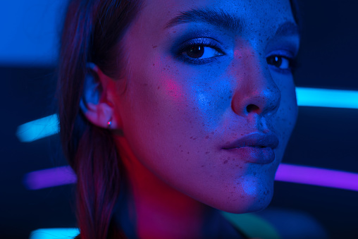 Studio portrait of a beautiful attractive athletic slim girl in blue and pink neon light.
