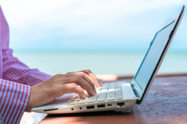 istock Woman hand using laptop to work study on work desk with clean nature beach outdoor background. Business, financial, trade stock maket and social network concept. 1250370035