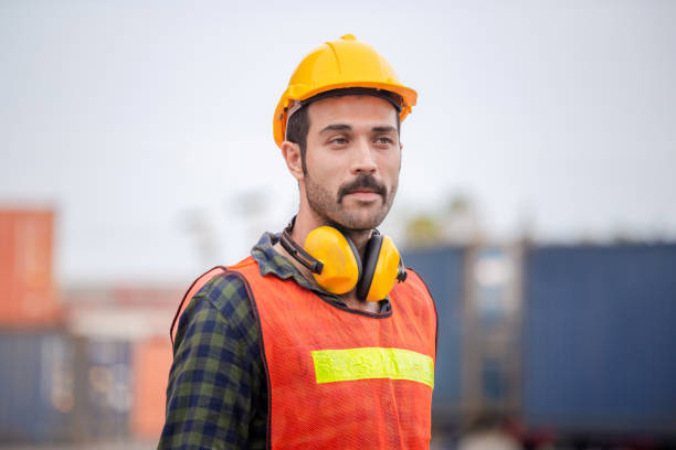 istock Engineer man in hardhat and safety vest, worker with protective headphones at construction site 1250372392