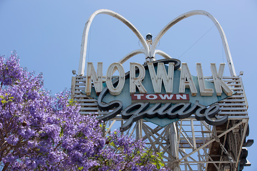 Norwalk, California / USA - May 24, 2020: Sun shines on the historic Norwalk Town Square sign in Norwalk, California.