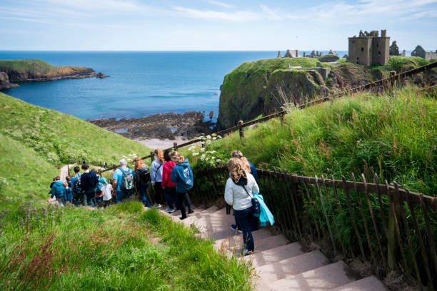 Stonehaven, Scotland, UK - June 22, 2019: A group of tourists and locals walk down a long flight of stairs to reach the entrance of  Dunnottar Castle which sits on a formidable cliff-top along the northeastern coast of Scotland in Stonehaven.