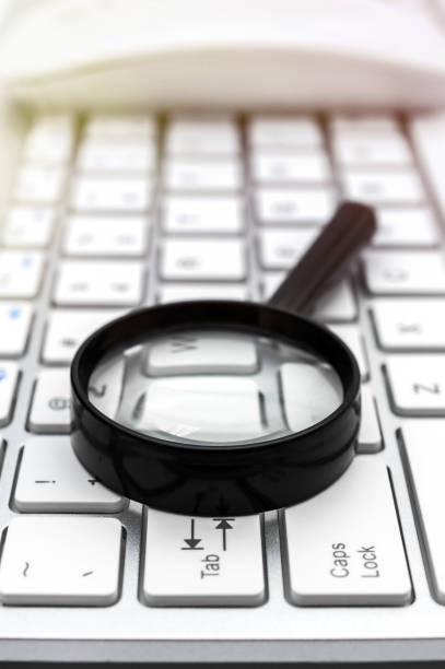 istock Magnifying glass with mouse on computer keyboard. Close up. 1250379137