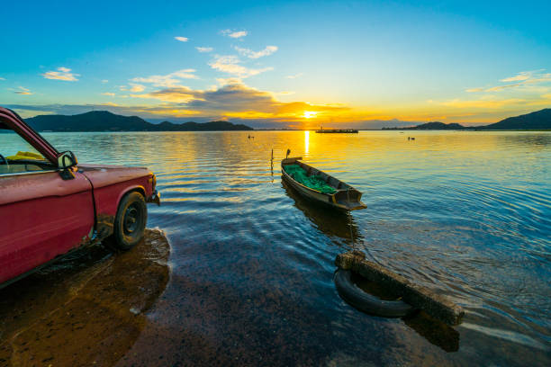 Old pickup truck parked on the waterfront with sunset at Bang phra reservoir ,sriracha chon buri,  thailand stock photo