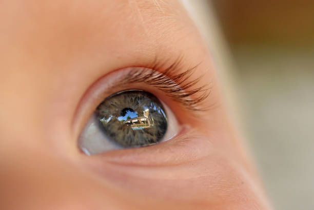 A close up image of a young boys eye with the reflection of a house in the background