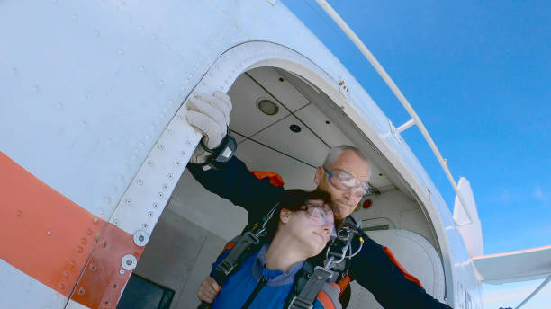 instructor and woman are jumping out of an airplane with a parachute. - parachuting open parachute opening imagens e fotografias de stock