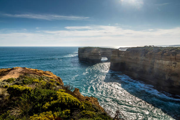 vista dalla great ocean road sulla costa vicino al london bridge a victoria, in australia, in una giornata di sole in estate. - formazioni calcaree london arch foto e immagini stock