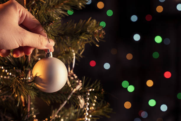 istock Christmas background concept- beautiful decor bauble hanging on the Christmas tree with sparkling light spot, blurry dark black background. 1250397621