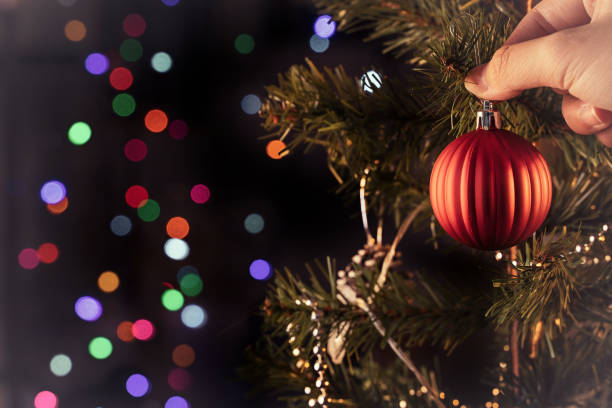 istock Christmas background concept- beautiful decor bauble hanging on the Christmas tree with sparkling light spot, blurry dark black background. 1250397652