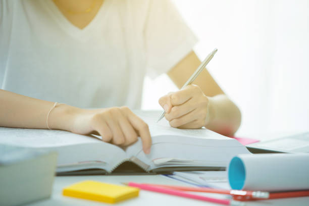 istock woman's hand with pen writing on book 1250399624