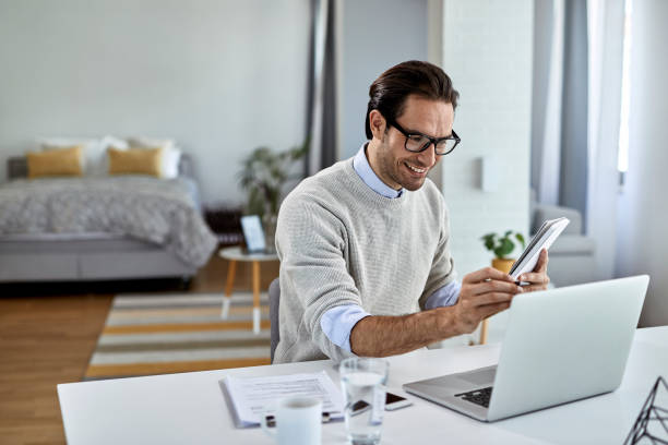 istock Young happy businessman using laptop while working at home. 1250400738
