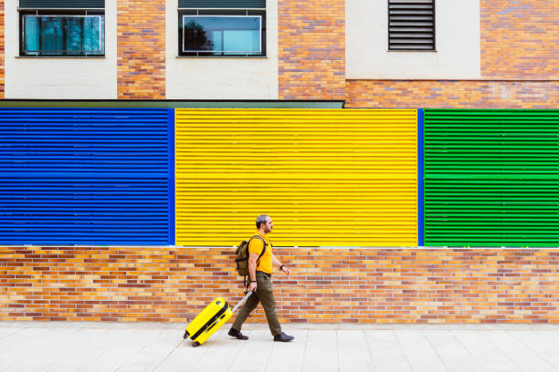 istock man traveling with suitcase and backpack on the street 1250404092