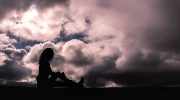 istock Young girl in silhouette on a cloudy sky 1250405360