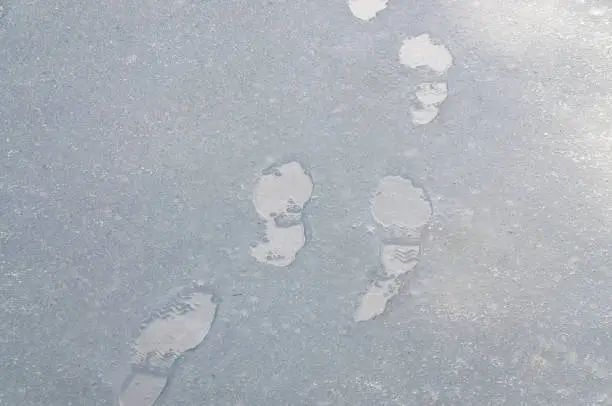 close up of wet footprints on a road covered with sleet