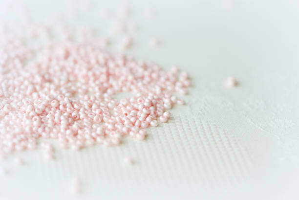 繊維の背景に散らばったピンクの種ビーズ手作りのコンセプト - plastic hole heap close up ストックフォトと画像