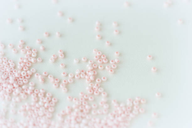 istock Pink seed beads scattered on the textile background close up. Handmade concept 1250410169