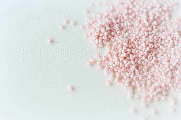繊維の背景に散らばったピンクの種ビーズ手作りのコンセプト - plastic hole heap close up ストックフォトと画像