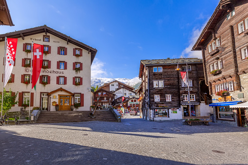 Zermatt, Switzerland - October 7, 2019: Town main street view in famous swiss ski resort, Gemeindehaus, mountains and people
