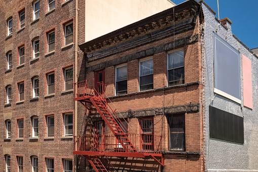 New York City old apartment buildings with steel fire escape stairways and copy space signs