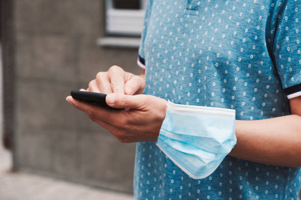 istock man using his smartphone wearing a mask in his arm 1250417941
