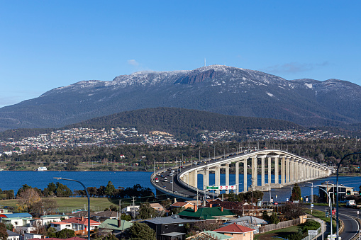 View of Mount Wellington Hobart and the Tasman Bridge, with some trees in the roof houses in the foreground, Hobart, Tasmania, Australia