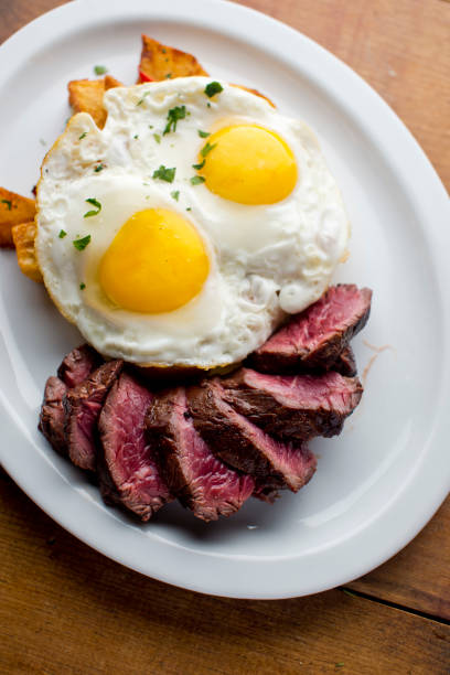 istock Steak and eggs. Classic breakfast or brunch favorite. Medium rare skirt steak served with eggs over easy and spicy country potato hash with onions and red bell peppers. 1250419231