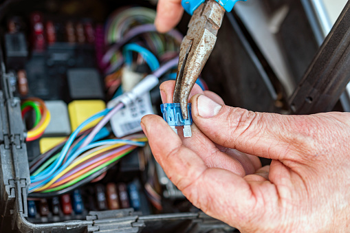 Mechanic with pliers checking the car fuse box of car