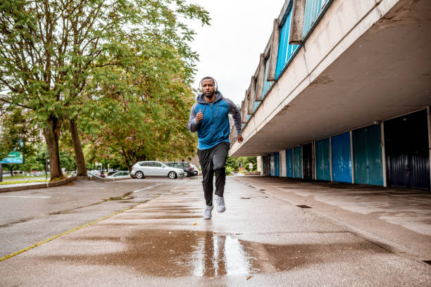 istock Young man running over the puddle by the garages 1250426972