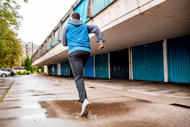 istock Young man running over the puddle by the garages 1250427086