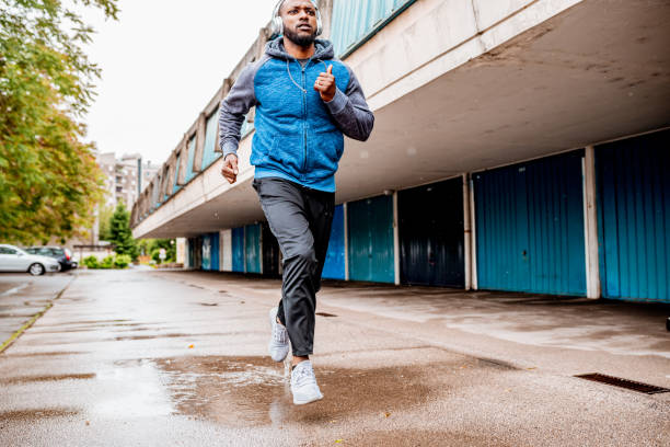 istock Young man running over the puddle by the garages 1250427162