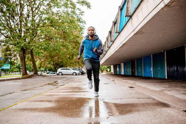 istock Young man running over the puddle by the garages 1250427256