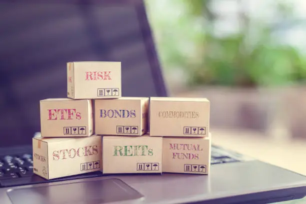 Photo of Boxes of financial products e.g risk, ETFs, bonds, commodity, stocks, REITs, mutual funds on a laptop