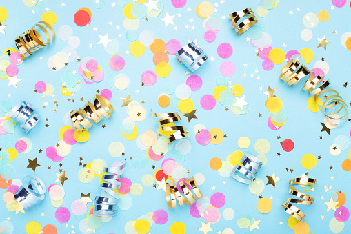 Birthday party background with confetti and streamer on blue. Top view.