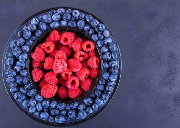 istock Fresh Organic Raspberries and Blueberries in Round Dish On Dark Background. 1250428719