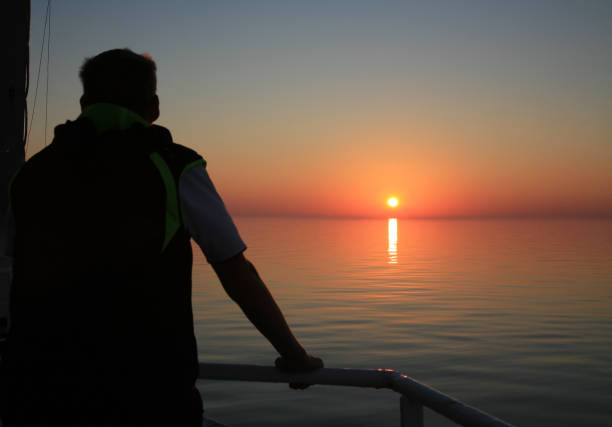 istock Young man on a ship during a cruise enjoys the sunrise 1250430135
