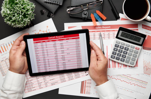 istock Top view of businessman's hands working with tablet pc and financial reports. Modern black office desk with notebook, pencil and a lot of things. Flat lay table layout. 1250430921