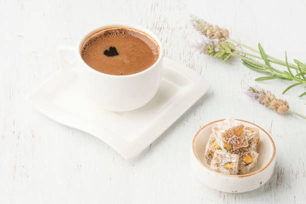 a cup of coffee and turkish delight on wooden table decorated with flowers