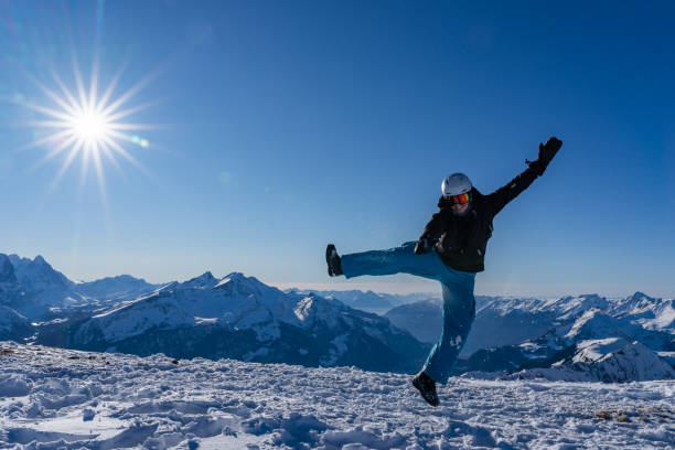 Girl with goggles and helmet is leaping midair in winter. stock photo