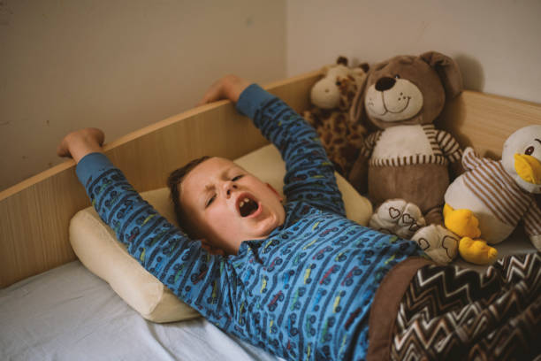 istock Little boy waking up stretching in bed 1250433934